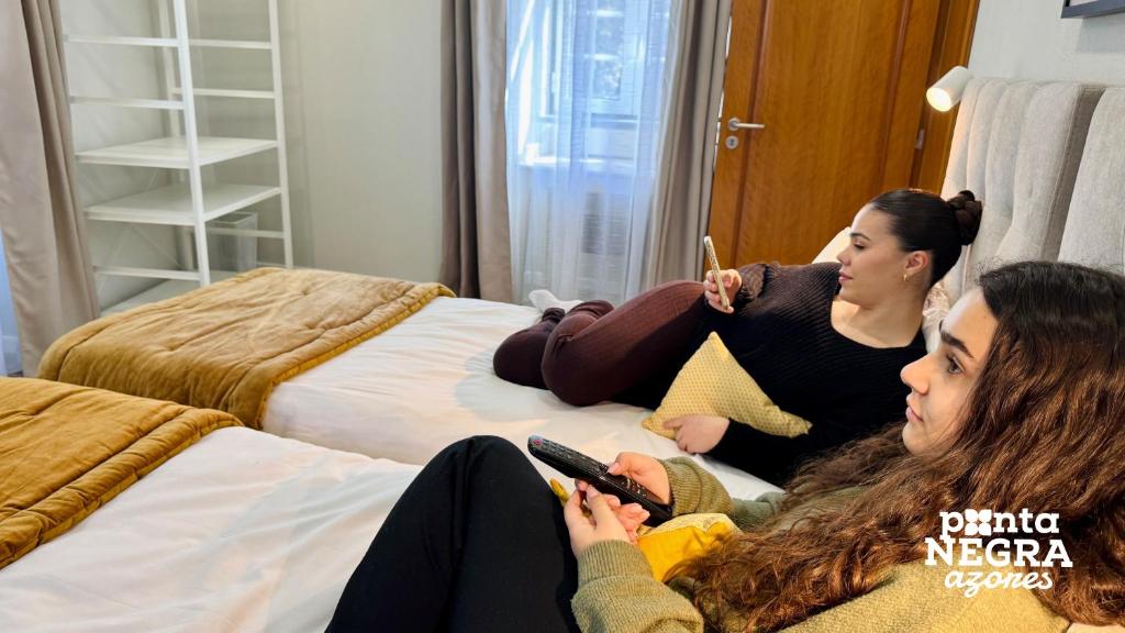 Two women on single beds in lodging room
